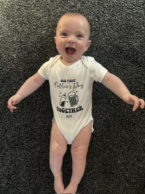 Baby boy wearing a happy fathers day baby gro